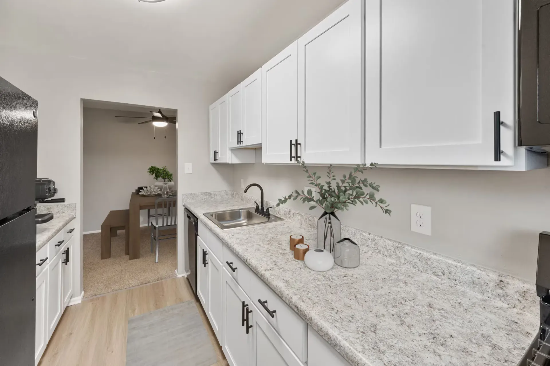 Bright galley kitchen with white cabinets, granite countertops, stainless sink, and small plant decor at The Ridge Apartments in Hagerstown, MD
