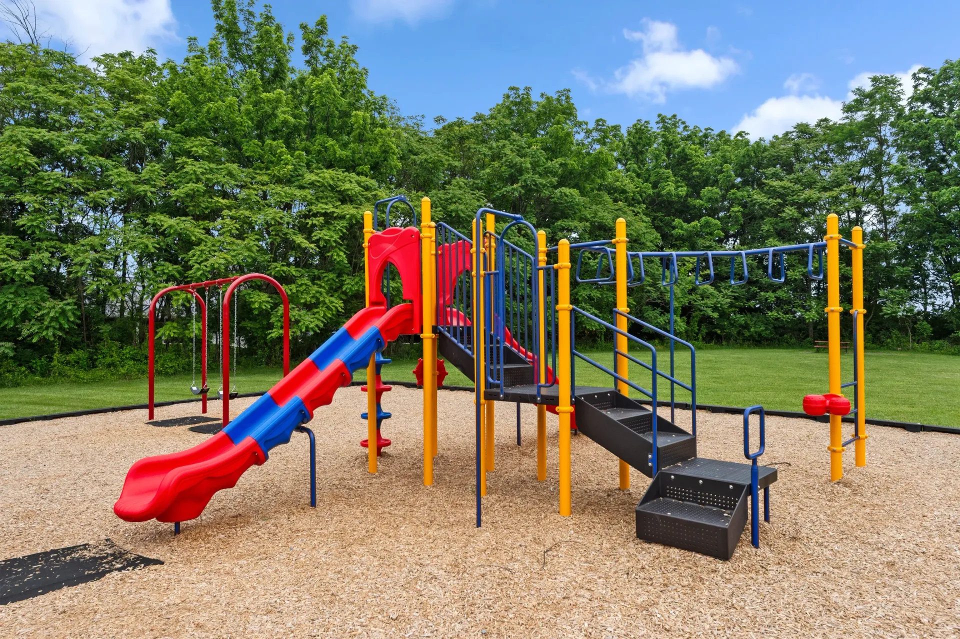 Colorful outdoor playground with slides, stairs and climbing bars on a wood-chip surface at The Ridge Apartments in Hagerstown, MD