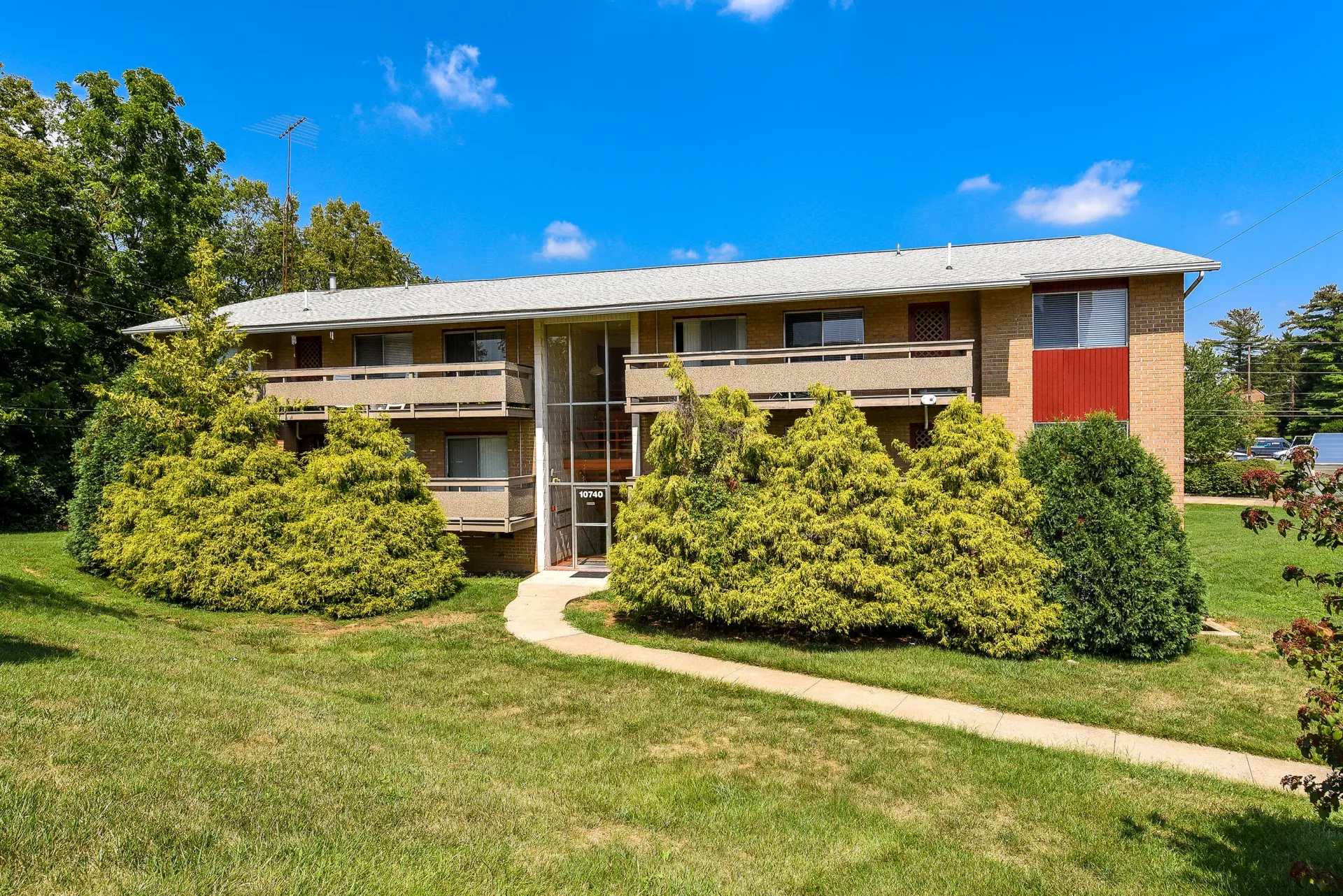Exterior view of a two-story brick apartment building with a central glass entry and landscaped shrubs at The Ridge Apartments in Hagerstown, MD