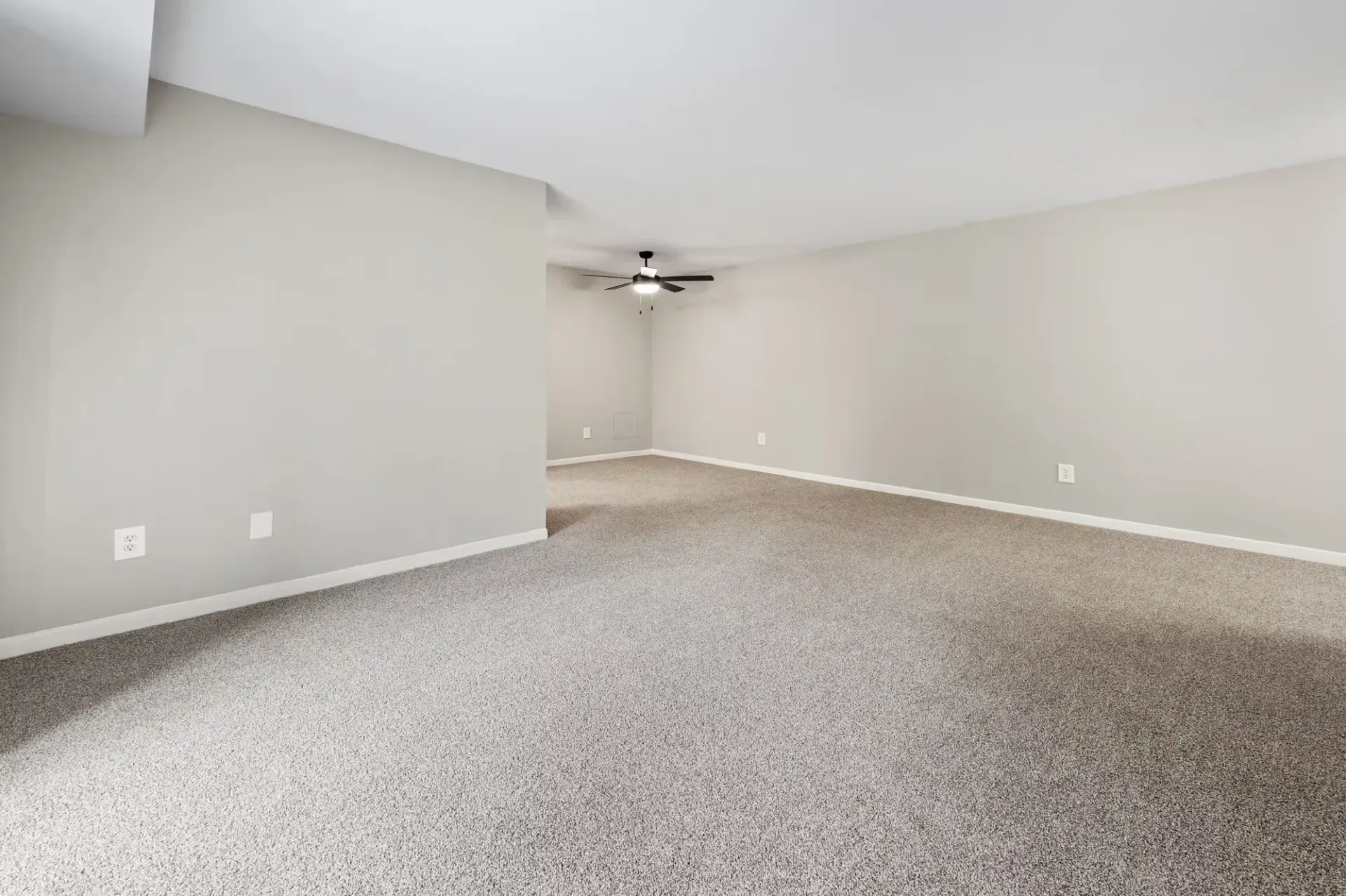 Empty living room in a neutral-toned apartment with carpet and a ceiling fan at The Ridge Apartments in Hagerstown, MD