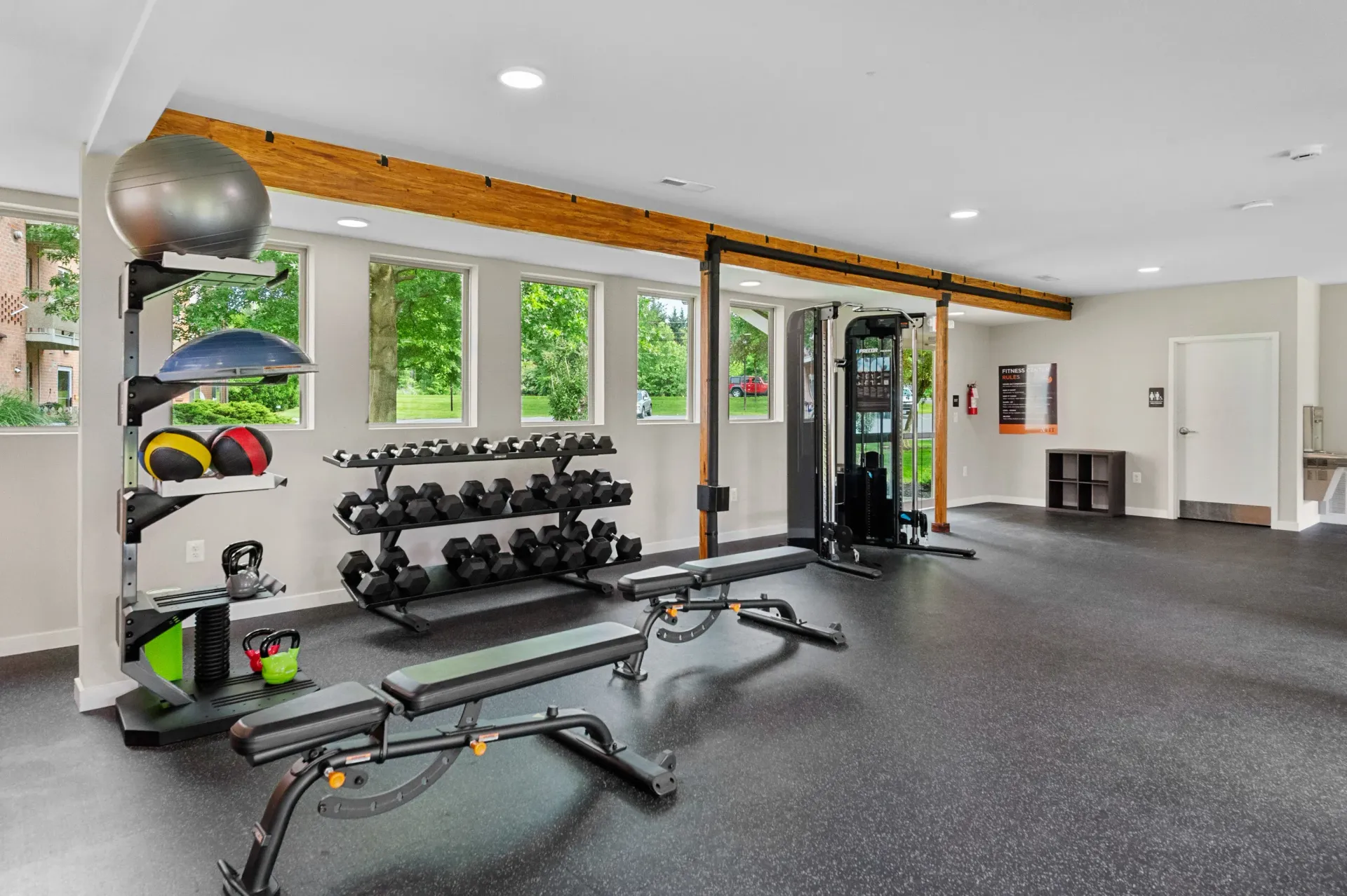 Indoor fitness center with dumbbells, benches, and a cable machine near windows at The Ridge Apartments in Hagerstown, MD