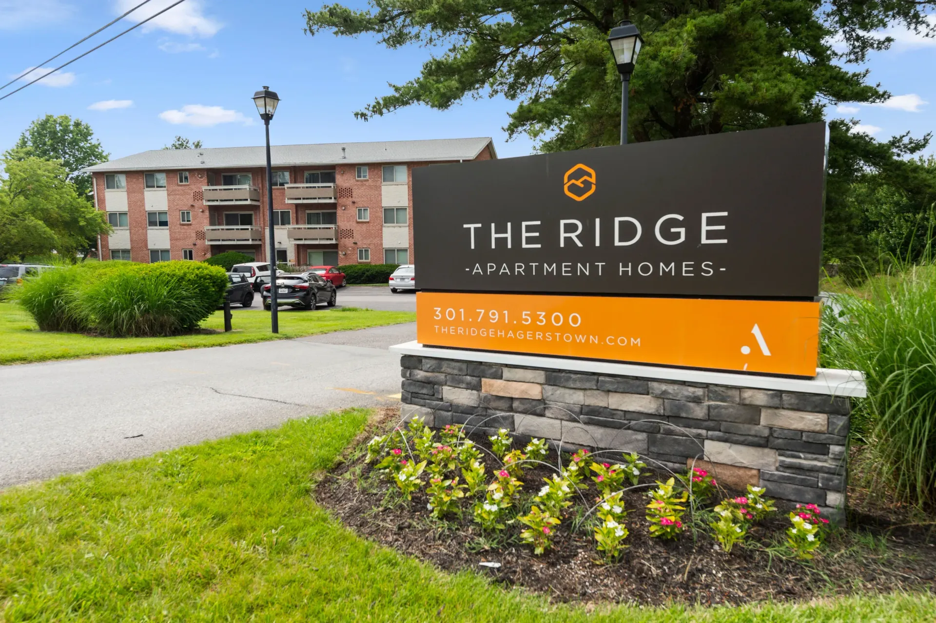 Exterior view of The Ridge Apartment Homes sign with a brick apartment building in the background at The Ridge Apartments in Hagerstown, MD