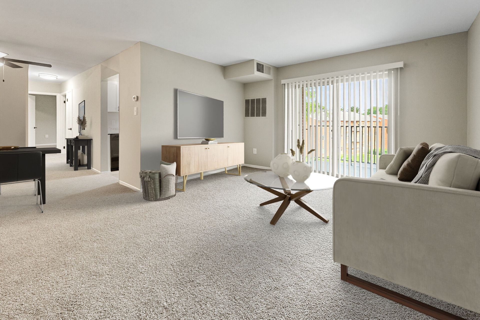 Living room in an apartment with a sofa, coffee table, wall-mounted TV, and sliding glass doors with vertical blinds at The Ridge Apartments in Hagerstown, MD.