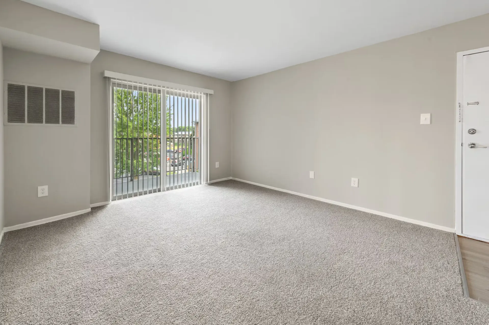 Living room with sliding glass door to balcony, neutral walls, and carpet at The Ridge Apartments in Hagerstown, MD