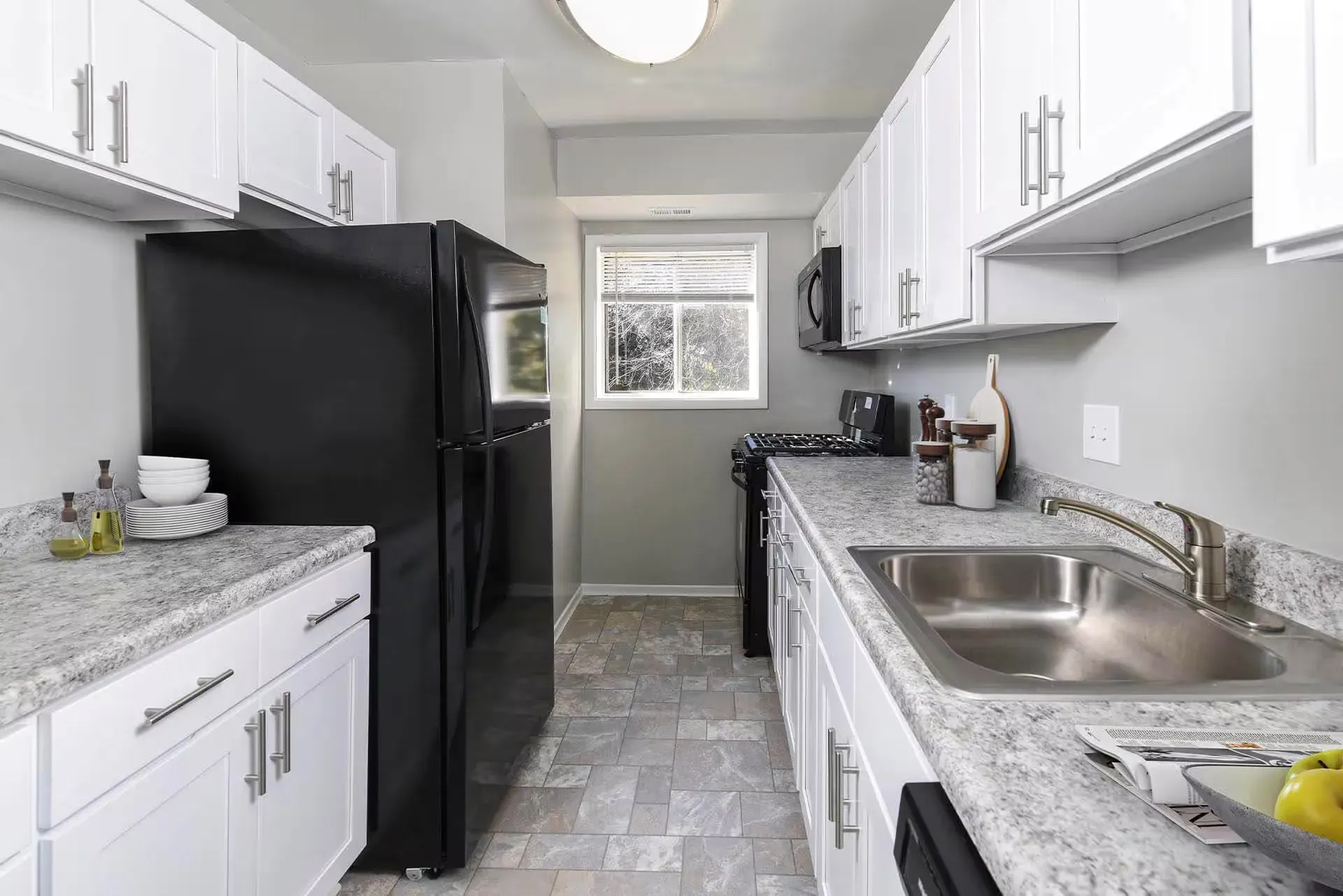 Modern galley kitchen with white cabinets, gray countertops, and stainless appliances at The Ridge Apartments in Hagerstown, MD