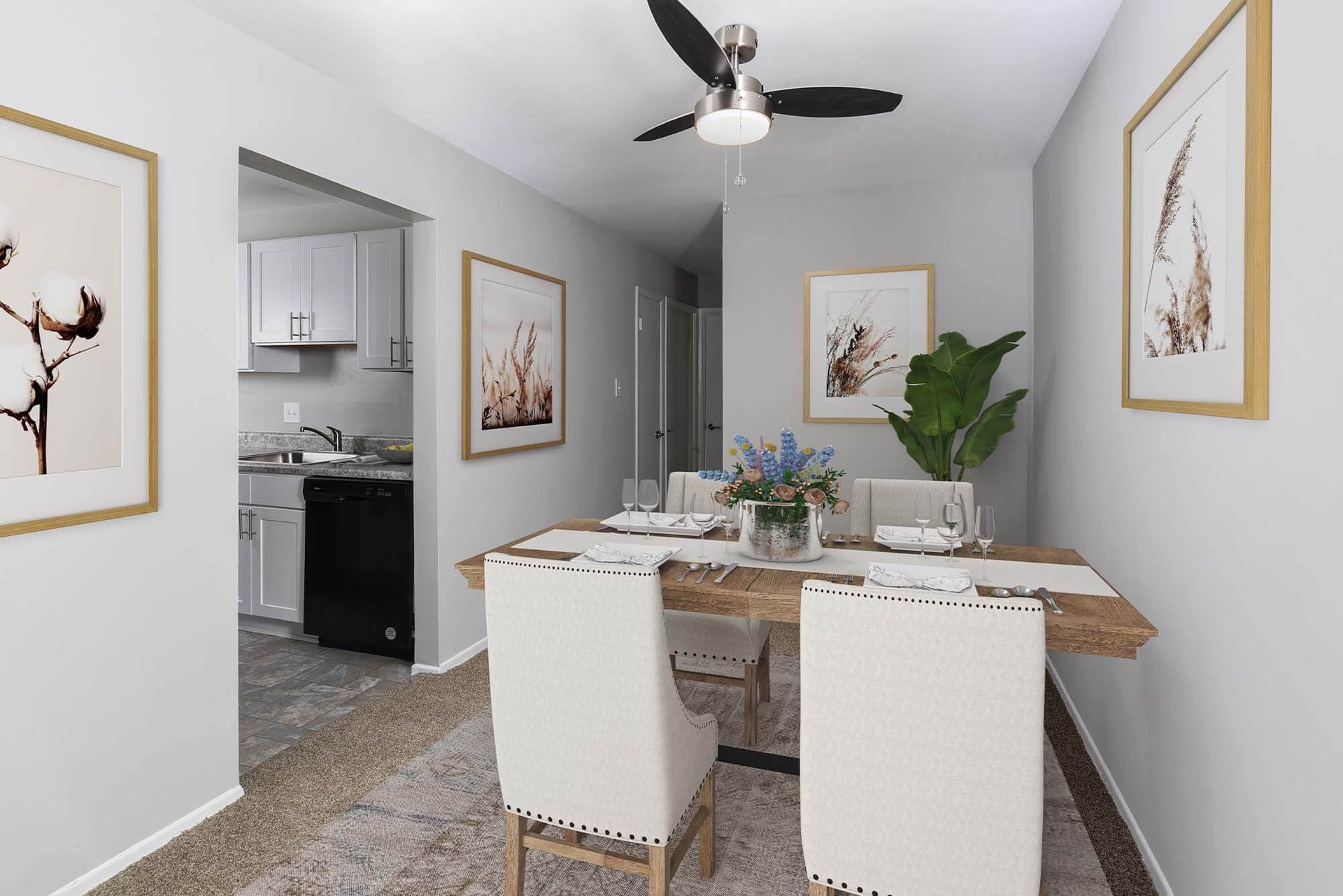 Dining area in an apartment with a wooden table, cream chairs, wall art, and a view into the adjacent kitchen at The Ridge Apartments in Hagerstown, MD