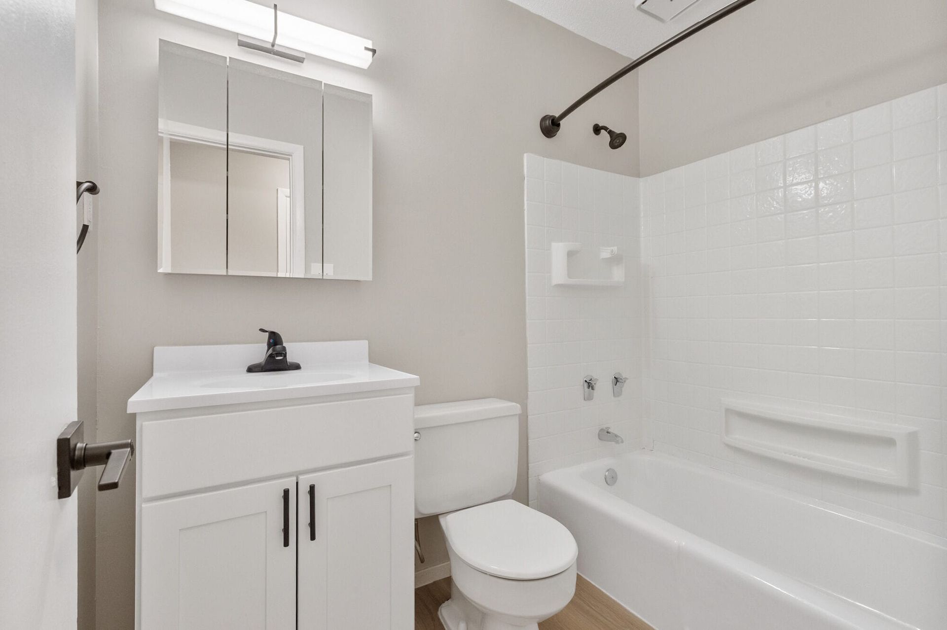White bathroom with vanity, mirror, toilet, and tub/shower enclosure at The Ridge Apartments in Hagerstown, MD