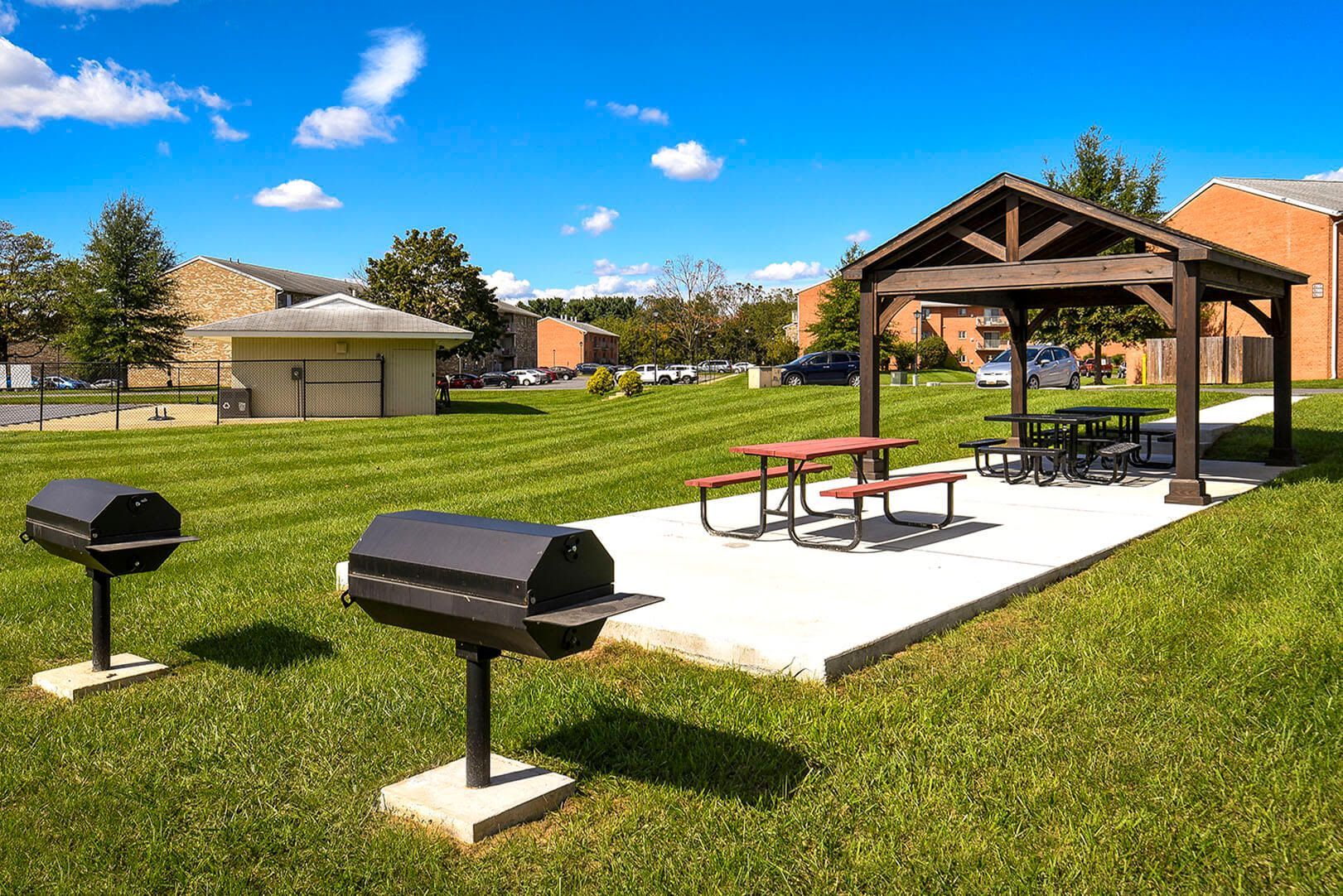 Outdoor community grill area with a wooden pavilion and picnic tables on a concrete pad at The Ridge Apartments in Hagerstown, MD