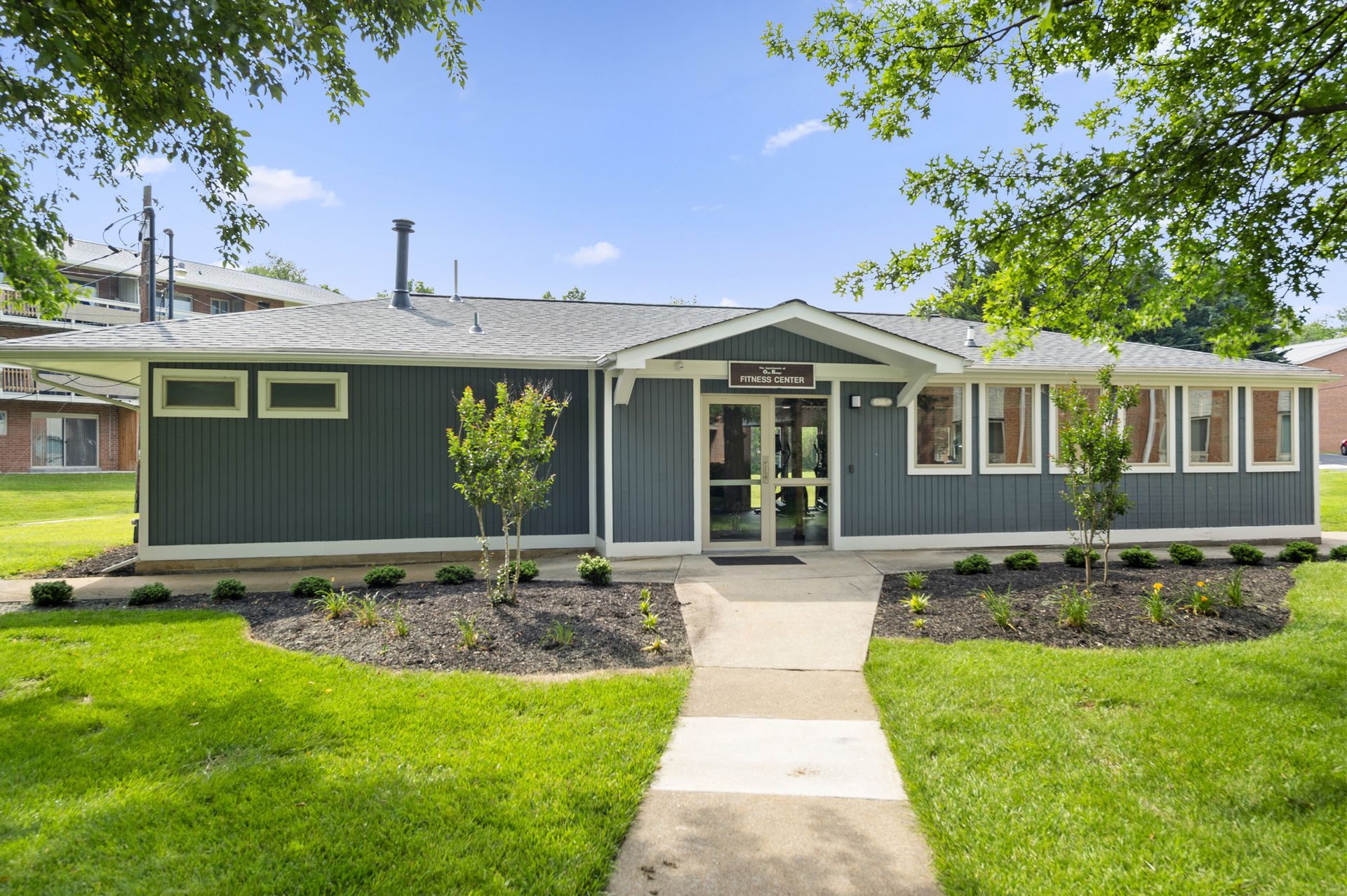 Exterior view of a single-story community fitness center with glass doors and landscaped path at The Ridge Apartments in Hagerstown, MD