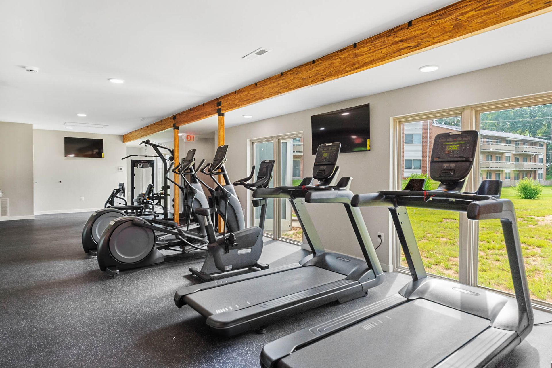 Indoor apartment gym with treadmills and elliptical machines by large windows at The Ridge Apartments in Hagerstown, MD