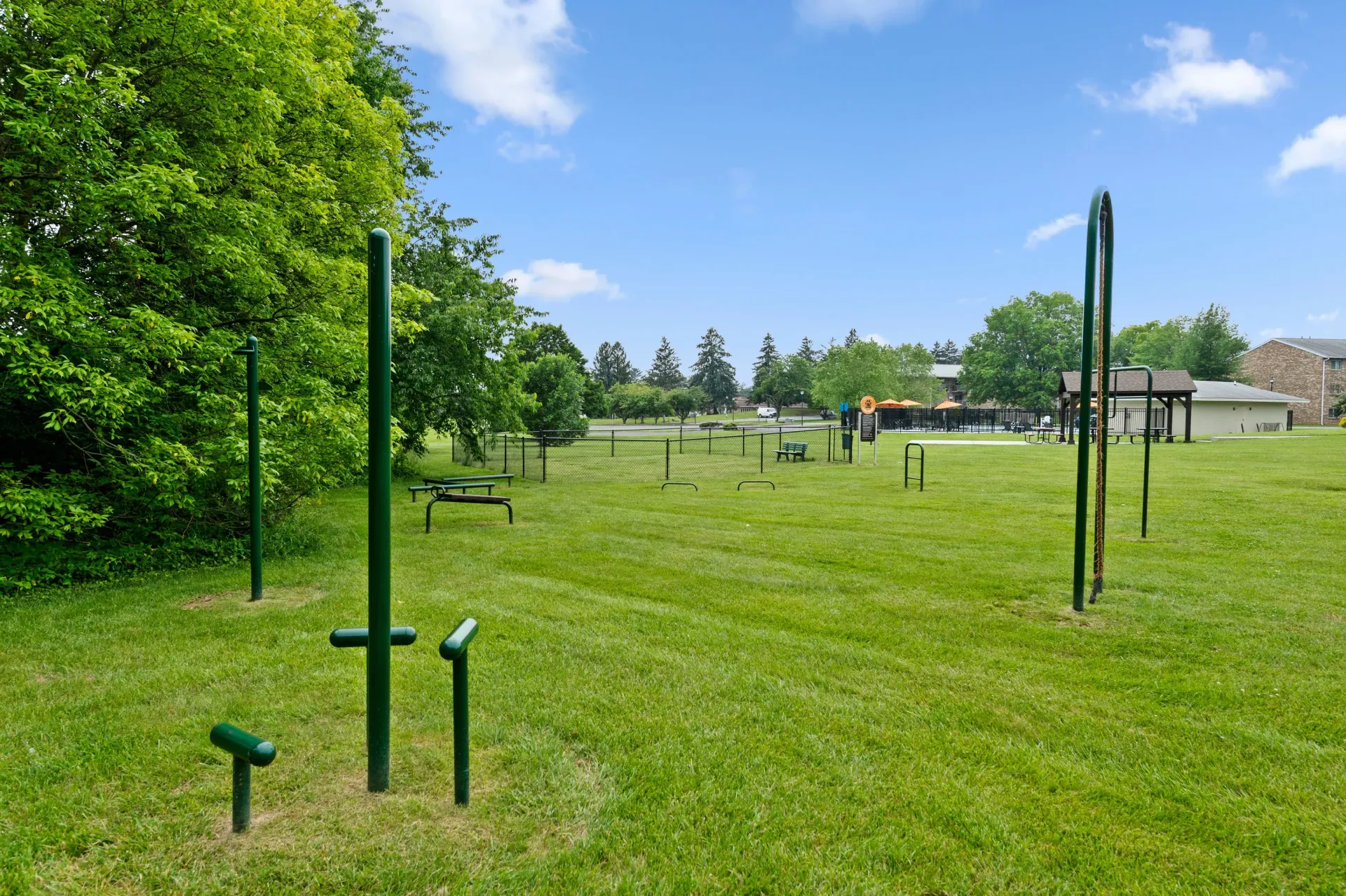 Outdoor community fitness park with green metal exercise stations on a grassy field at The Ridge Apartments in Hagerstown, MD