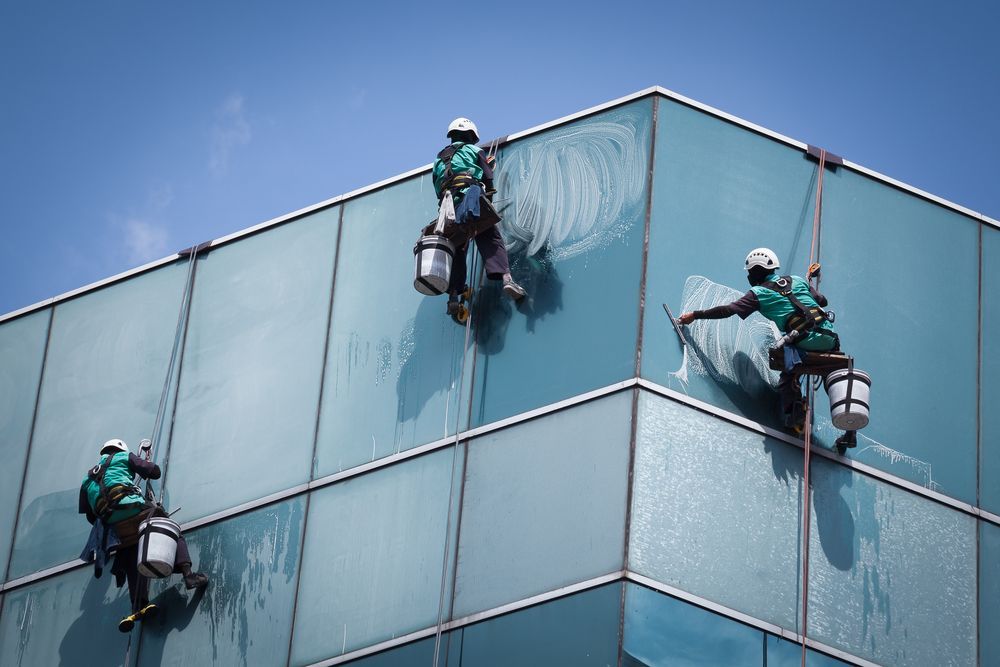 Three Men Are Cleaning The Windows Of A Tall Building — Dazzling Windows & Pressure Cleaning in Currumbin, QLD
