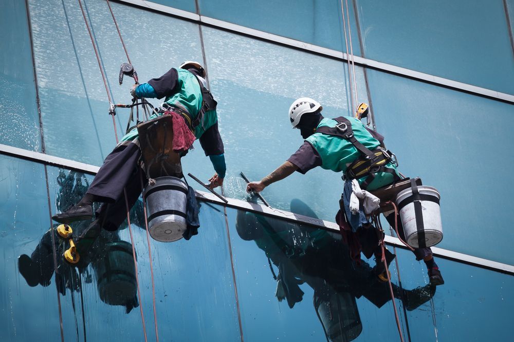 Two Men Are Cleaning the Windows of a Tall Building — Dazzling Windows & Pressure Cleaning in Tugun, QLD