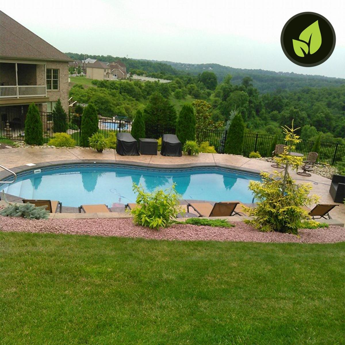 Swimming pool with lounge chairs, surrounded by greenery and overlooking a wooded valley.