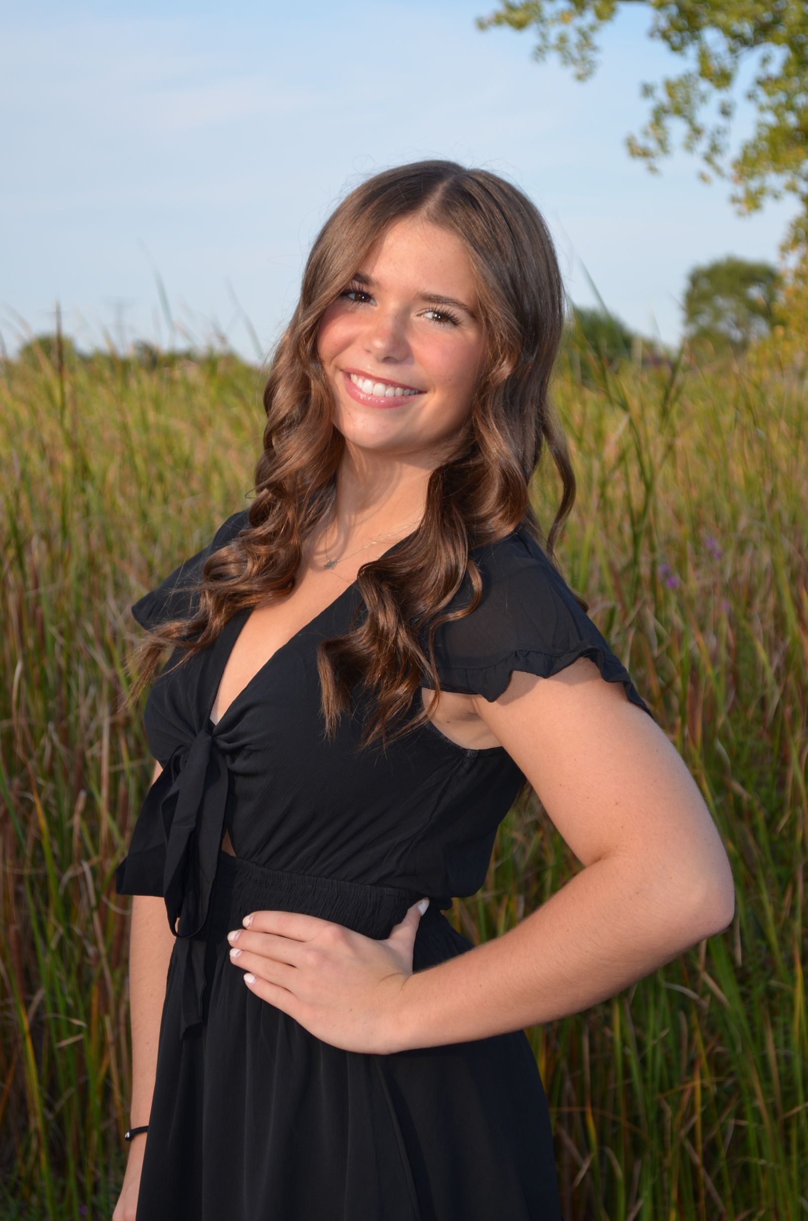 A woman in a pink dress is smiling and holding a bouquet of flowers.