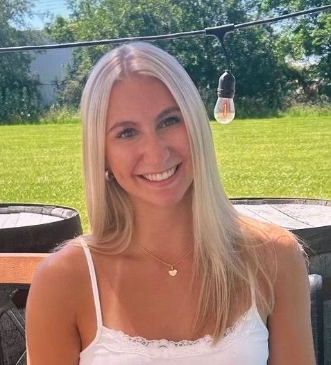 A close up of a woman smiling with a man in the background.