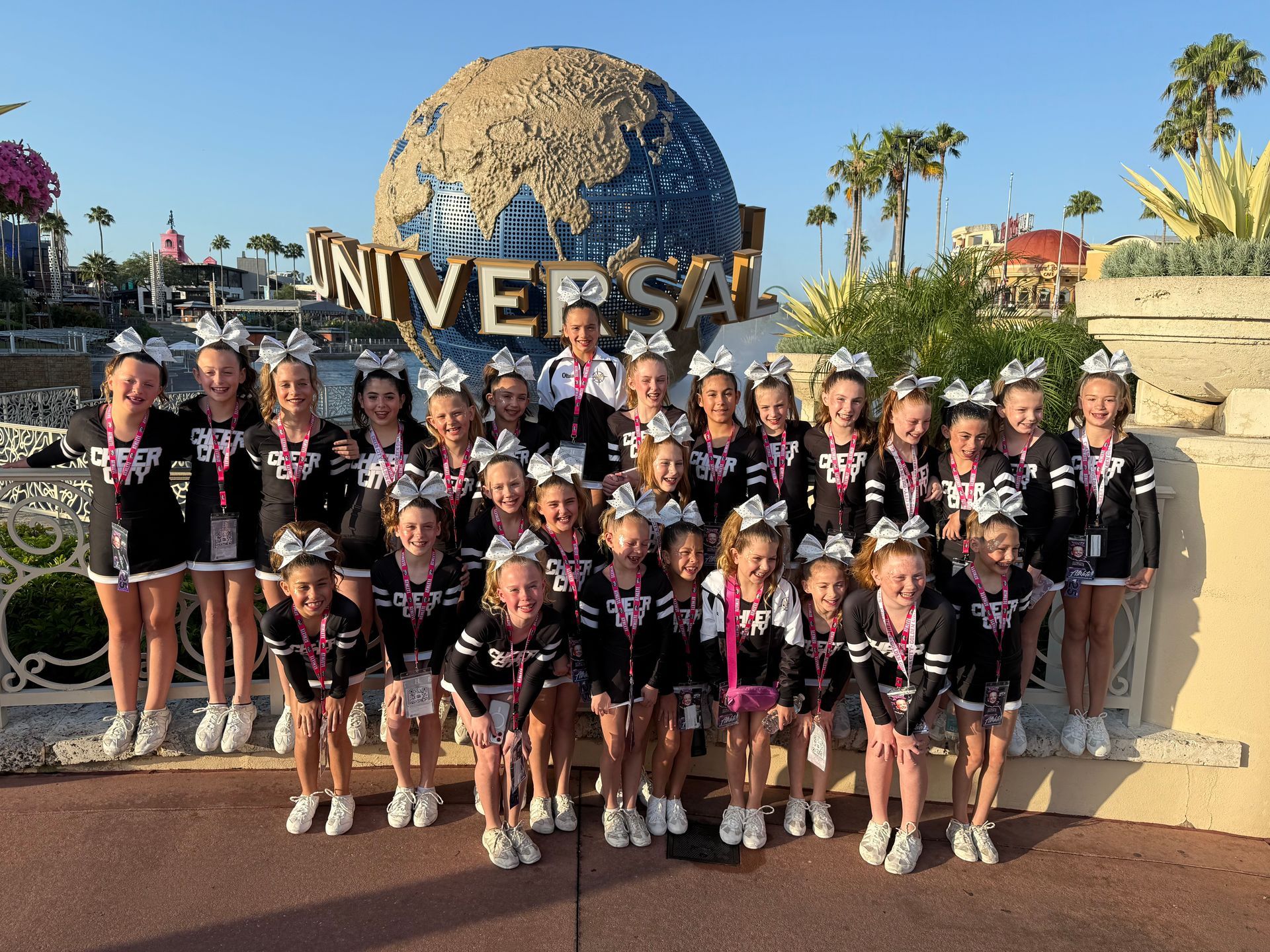 A group of cheerleaders are posing for a picture in front of a universal studios sign.