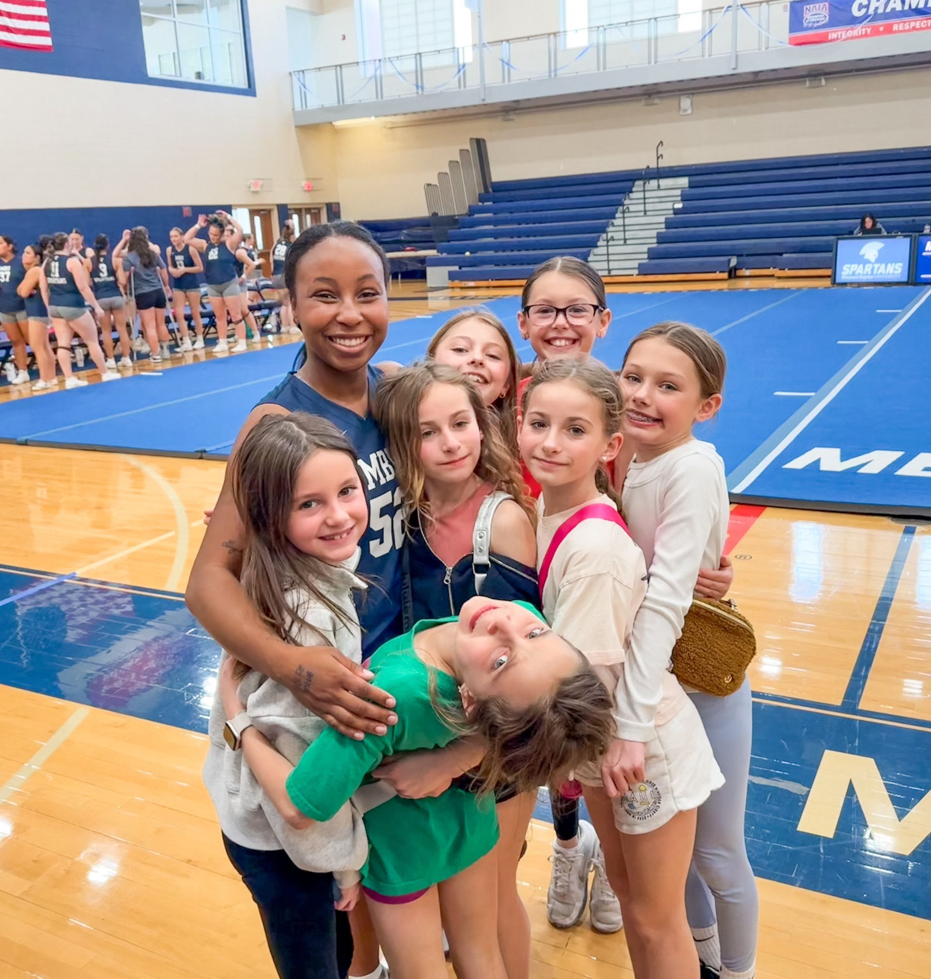 A group of young girls are posing for a picture on a basketball court.