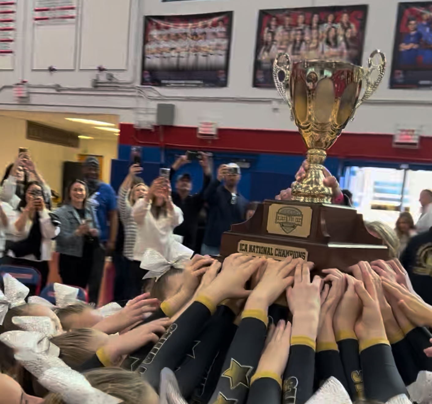 A group of cheerleaders are holding a trophy in their hands