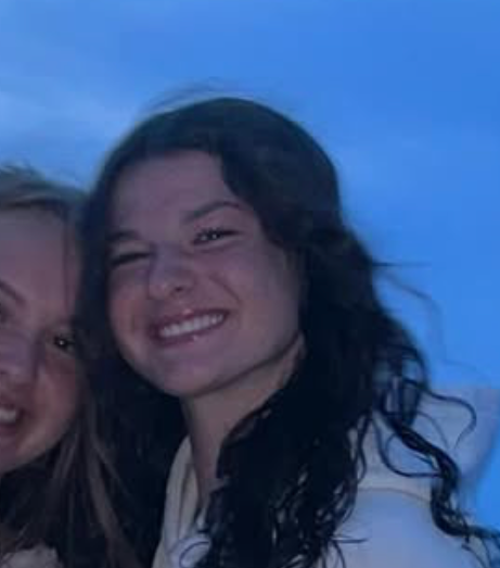 Two young women are posing for a picture together and smiling.