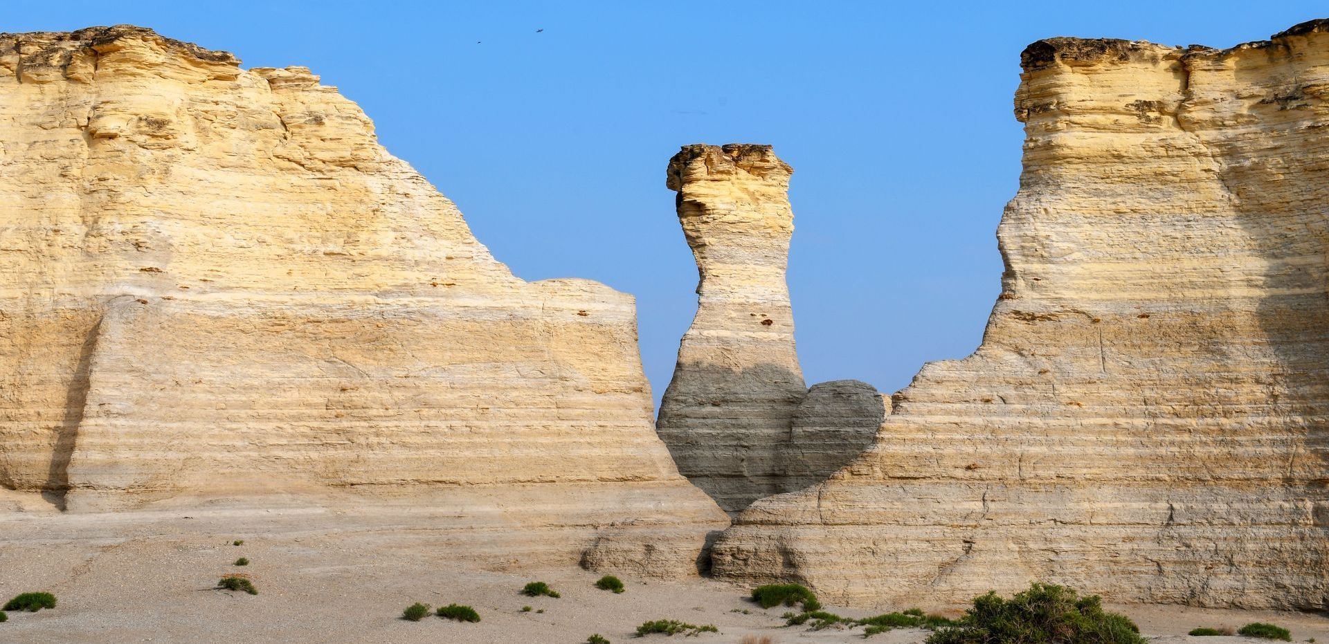 A large rock formation in the desert with a blue sky in the background