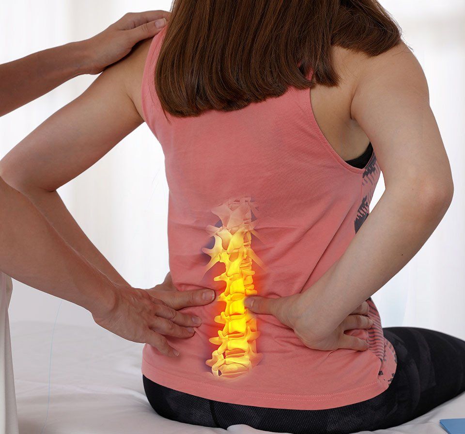 a woman is sitting on a bed with her back in pain .