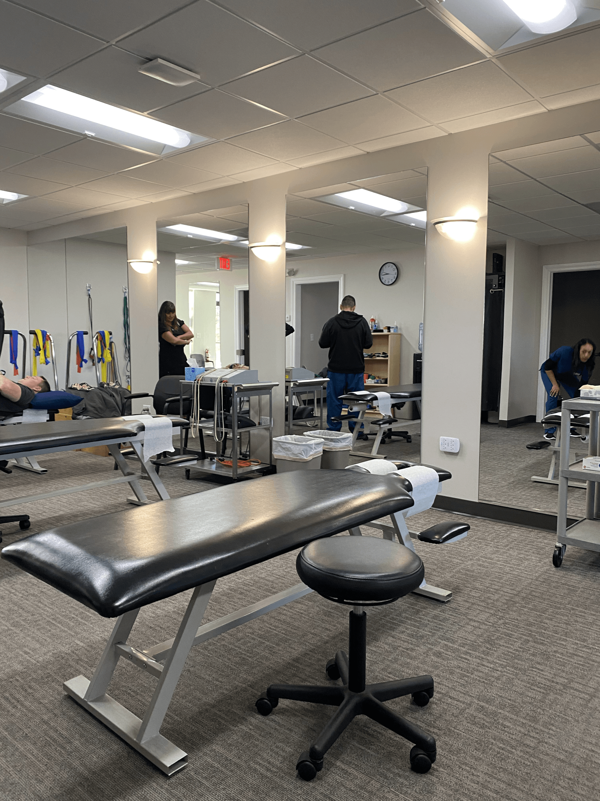 a physical therapy room with a lot of tables and mirrors .