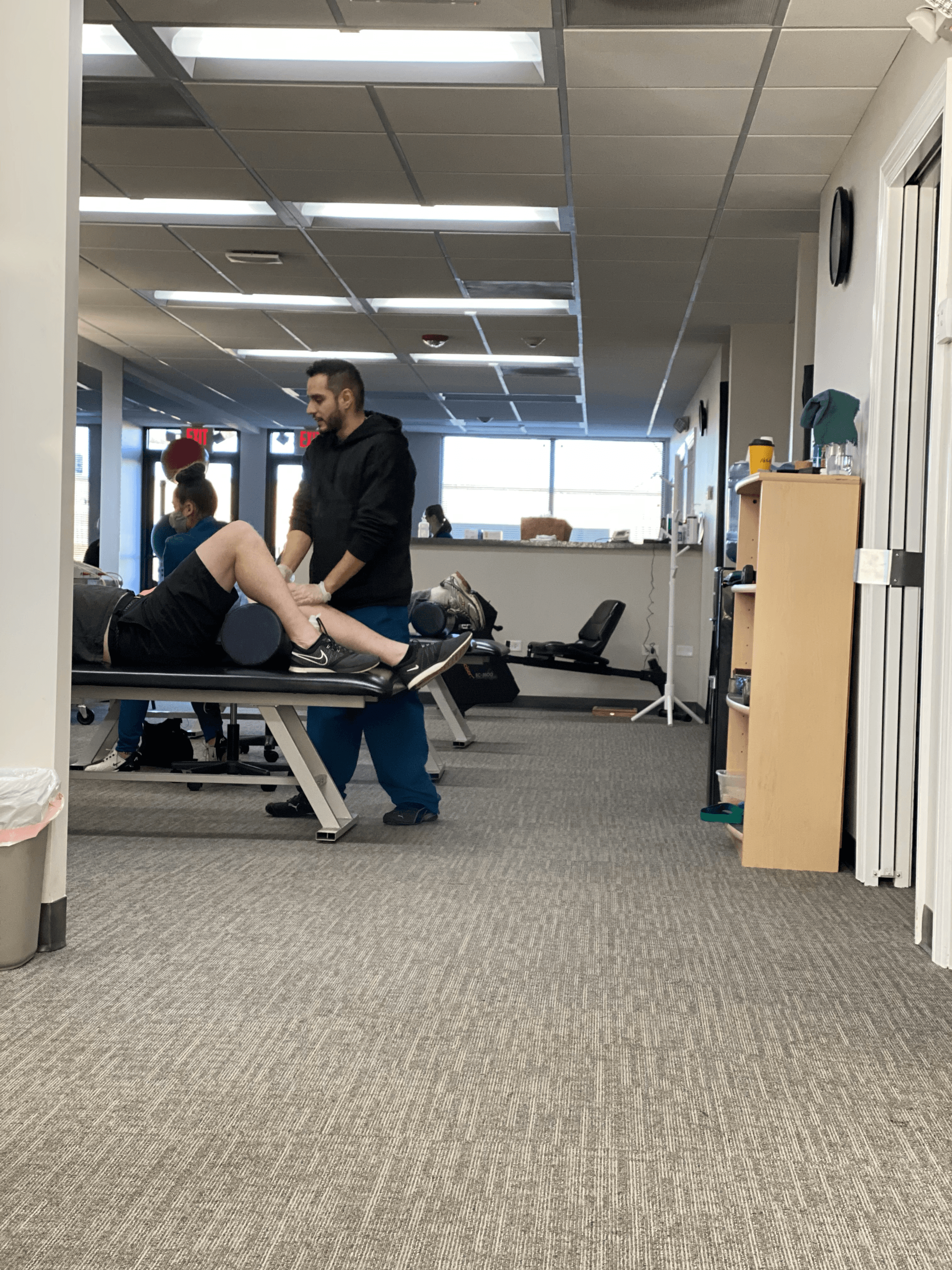 a man is stretching a woman 's leg in a gym .