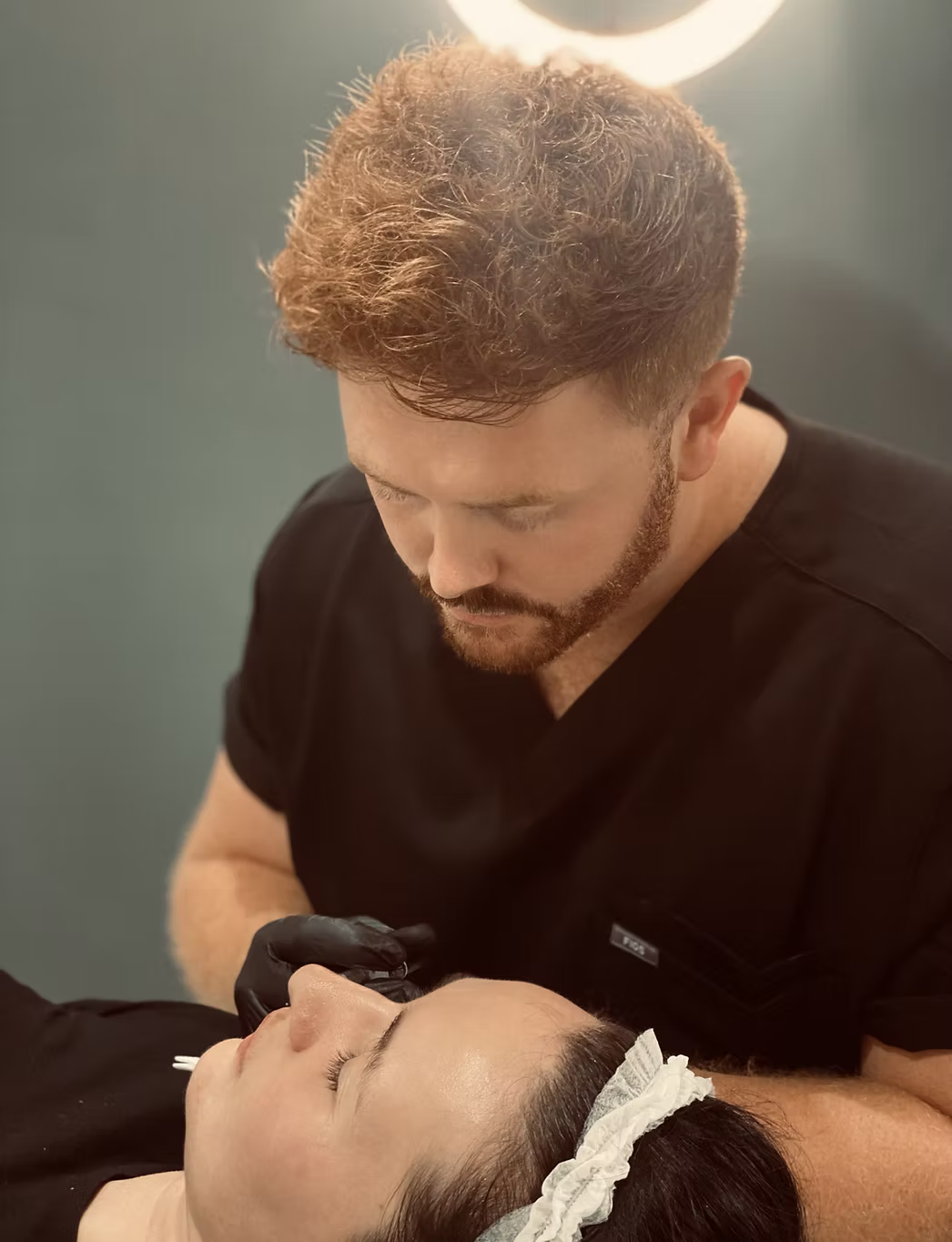 A man is giving a woman a facial treatment.