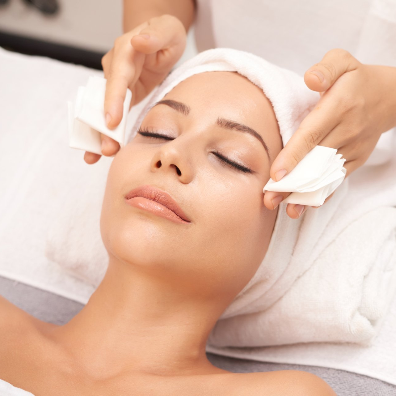 A woman with a towel wrapped around her head is getting a facial treatment