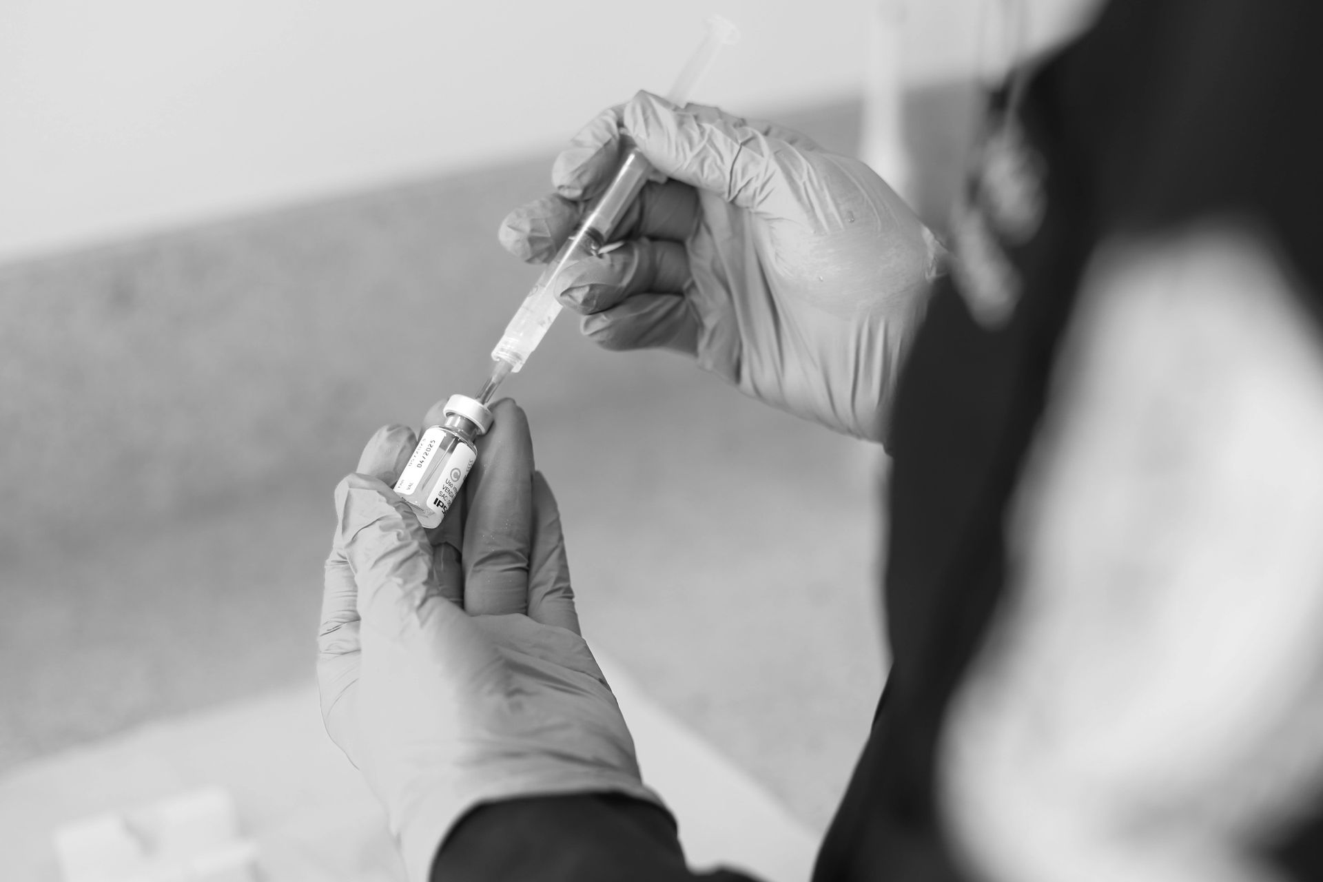 A person is holding a syringe and a bottle of vaccine.