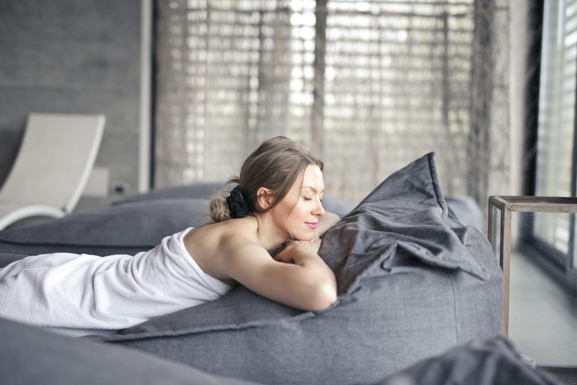 A woman wrapped in a towel is laying on a bed.