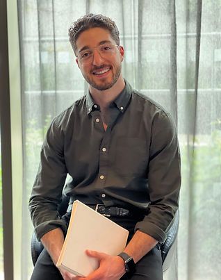 A man is sitting in a chair holding a piece of paper and smiling.