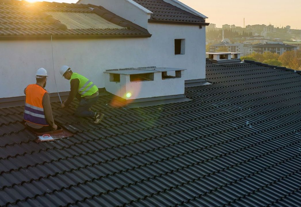 Two men are working on the roof of a house.