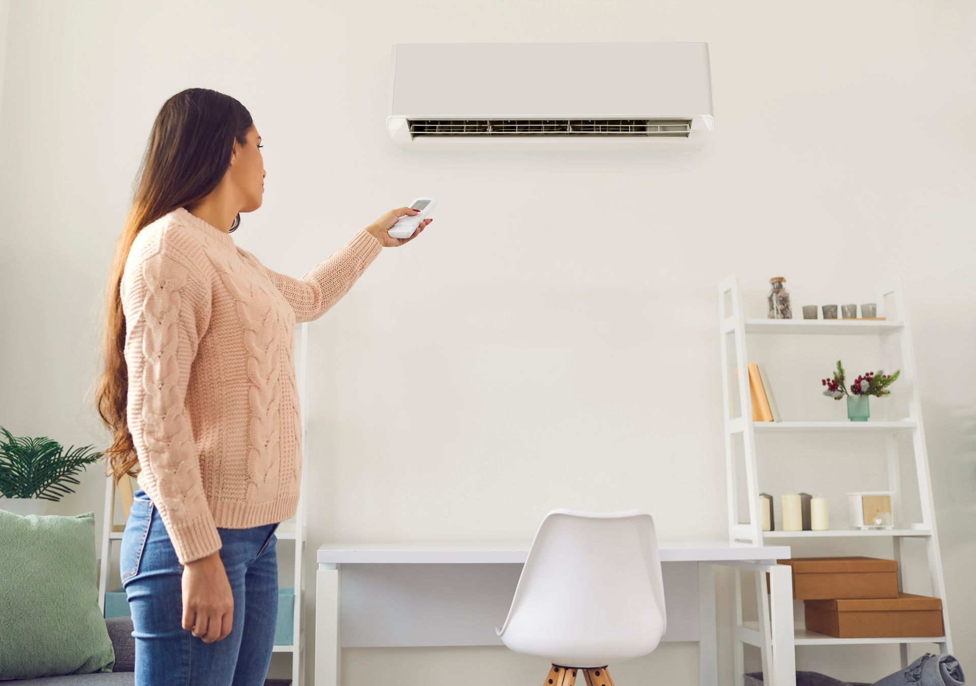 A woman adjusting the temperature of an air conditioner with a remote control.
