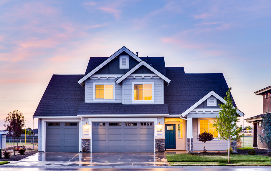 A large white house with a blue roof and a blue garage door.