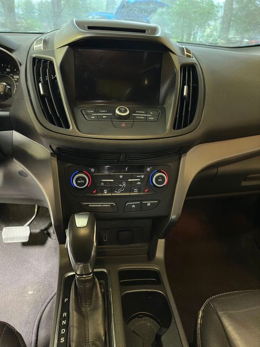 The dashboard of a ford escape with a touchscreen radio and climate control.