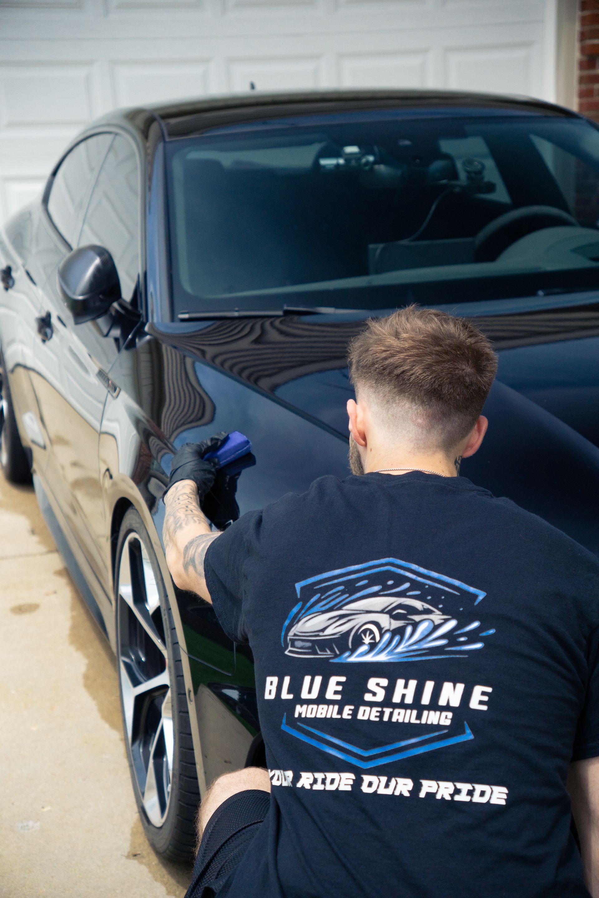 A man is cleaning the side of a black car.