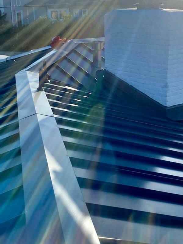 Metallic rooftop with bright sunlight reflecting off the ridges and edges.