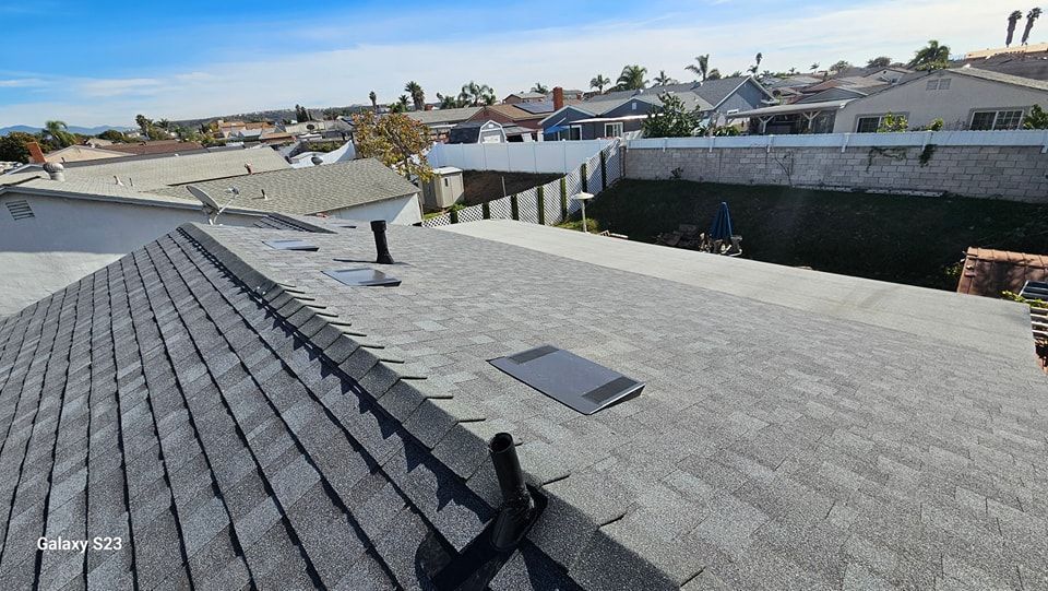 Gray shingle roof, view of surrounding houses and clear blue sky.