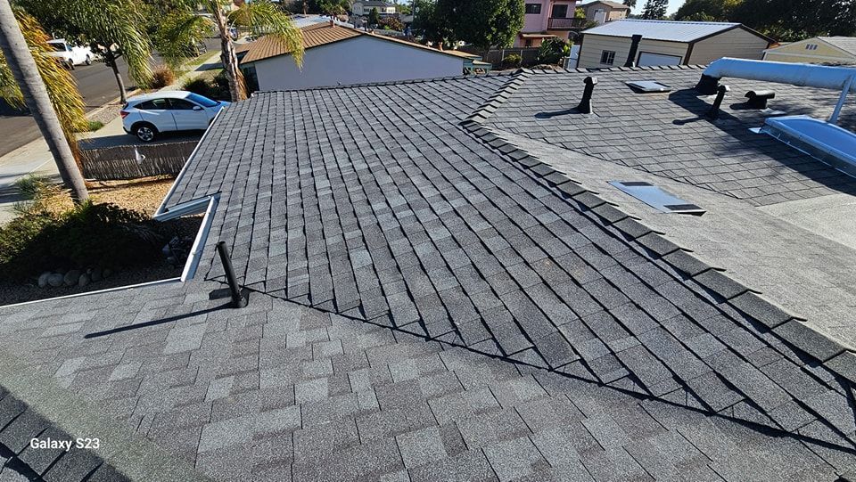 Gray asphalt shingle roof on a house, angled view, sunny day.