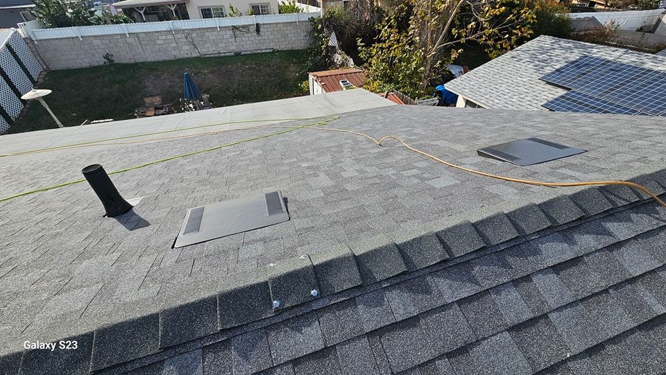 View of a rooftop with asphalt shingles, vents, and a flat section.
