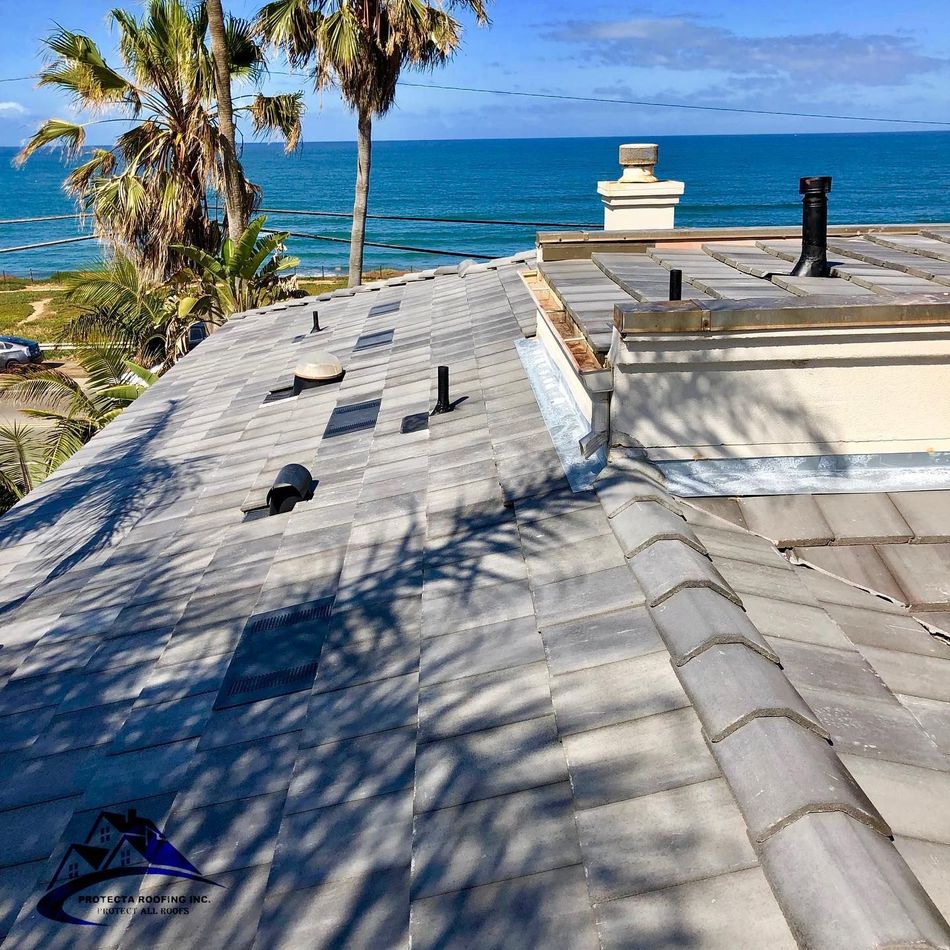 Tile roof with ocean view, palm trees in background.