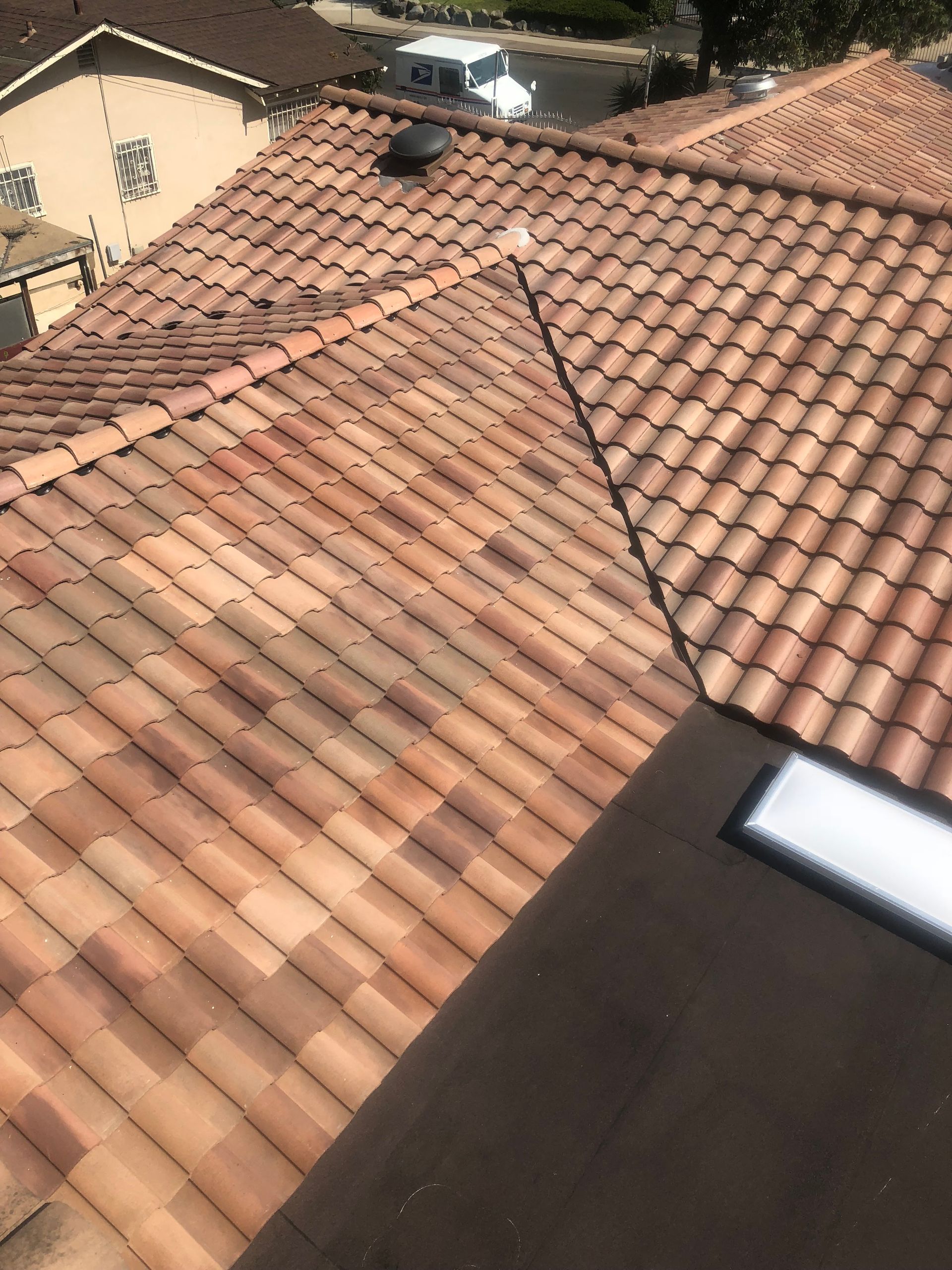 Tiled roof with varying shades of red and brown. A dark-colored vent and light-colored corner trim visible.