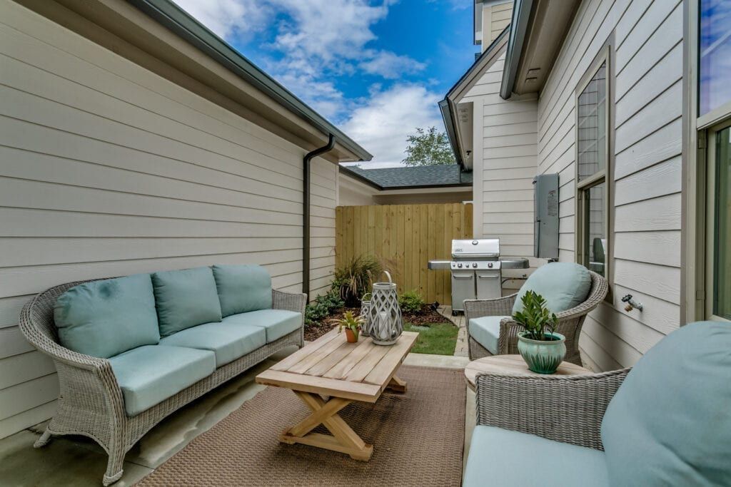 Outdoor patio with wicker furniture, a grill, and wooden fence.
