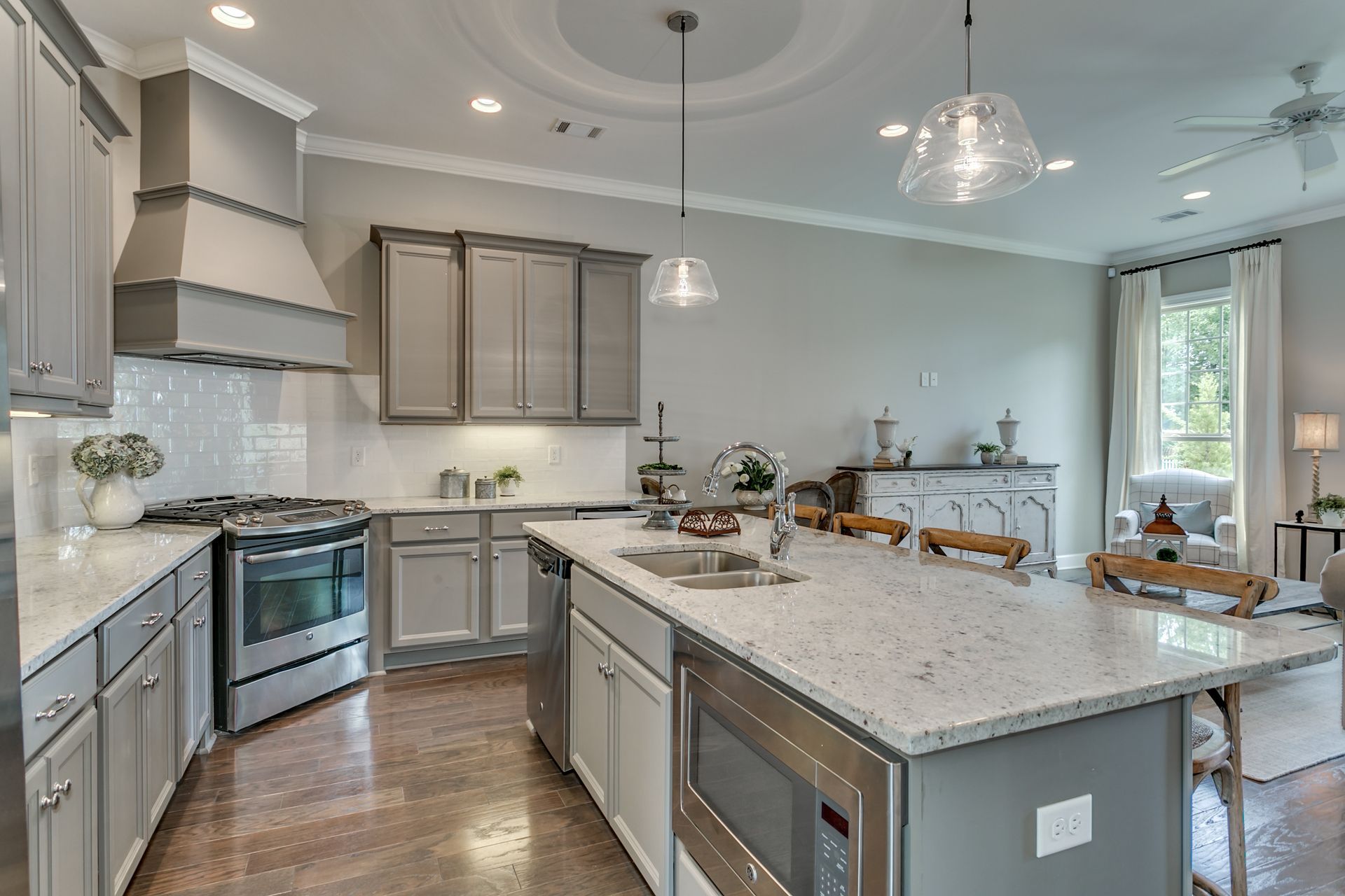 Modern kitchen with gray cabinets, stainless steel appliances, and large island with quartz countertop.