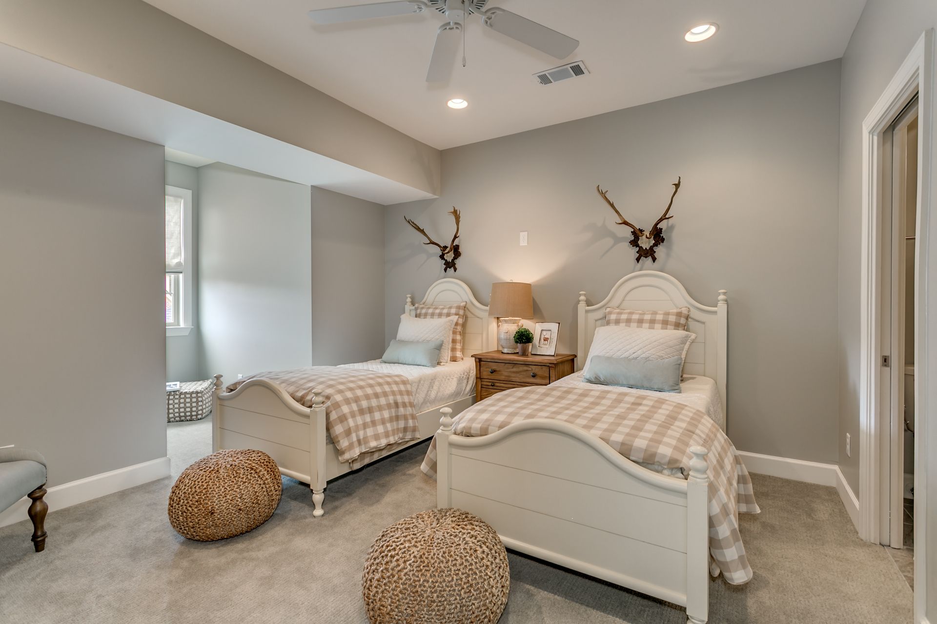 Bedroom with two twin beds, tan and white decor, rug, and ceiling fan.