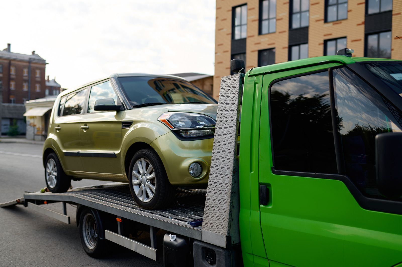A car is being towed by a green tow truck.