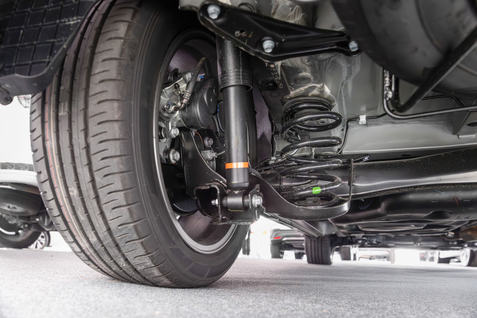 Rear car suspension system, black shock absorber, spring, and tire.