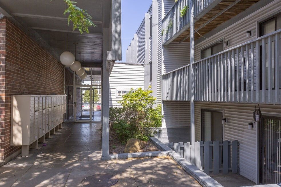 Apartment building exterior with a covered walkway, mailboxes, and balconies.